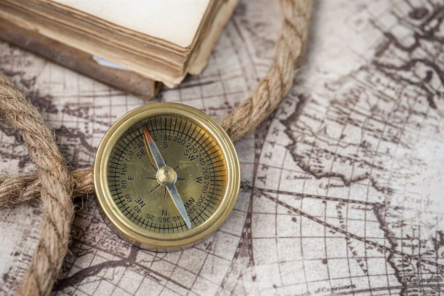 Vintage brass compass resting on an antique world map