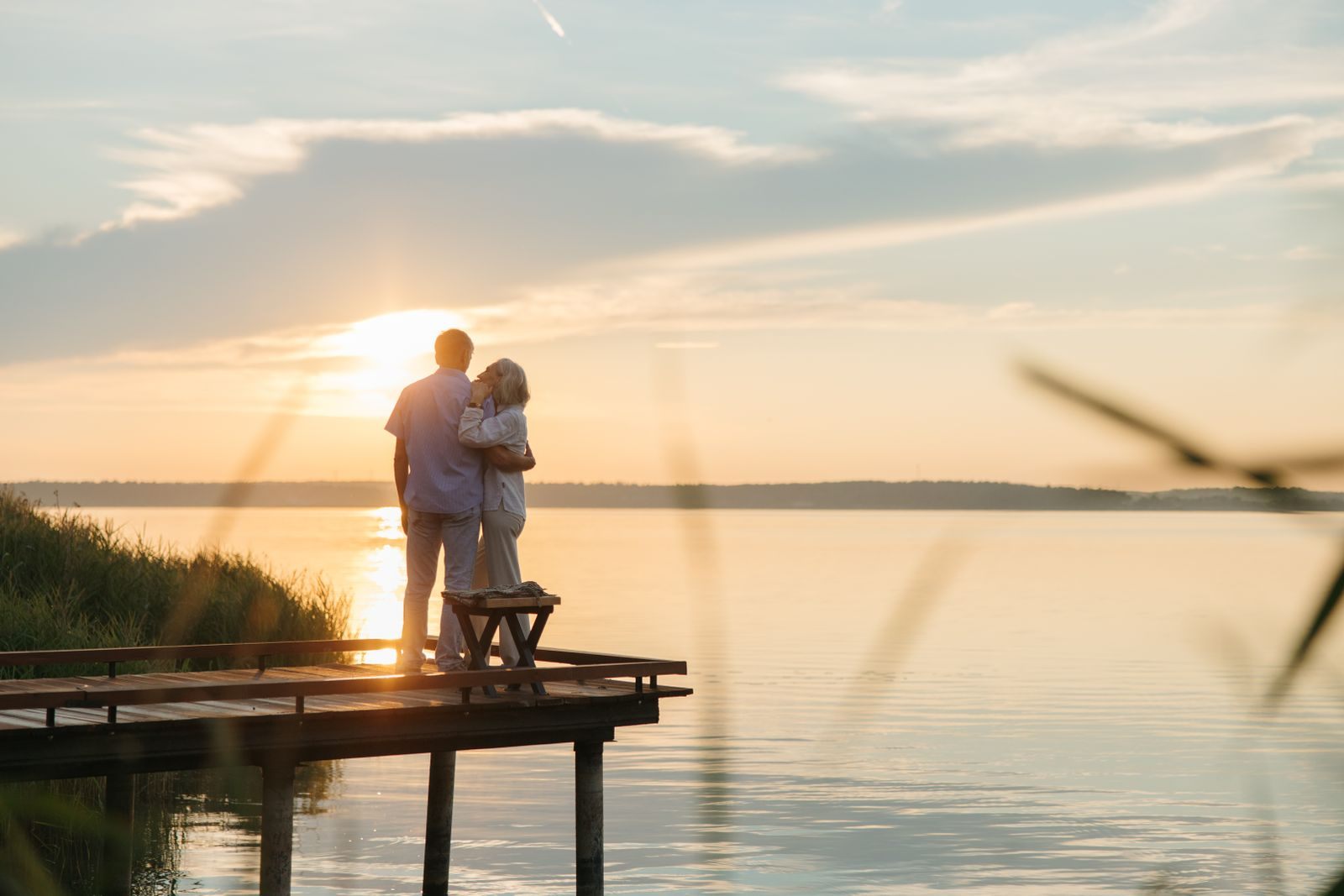 Senior couple embracing on a wooden dock at sunset