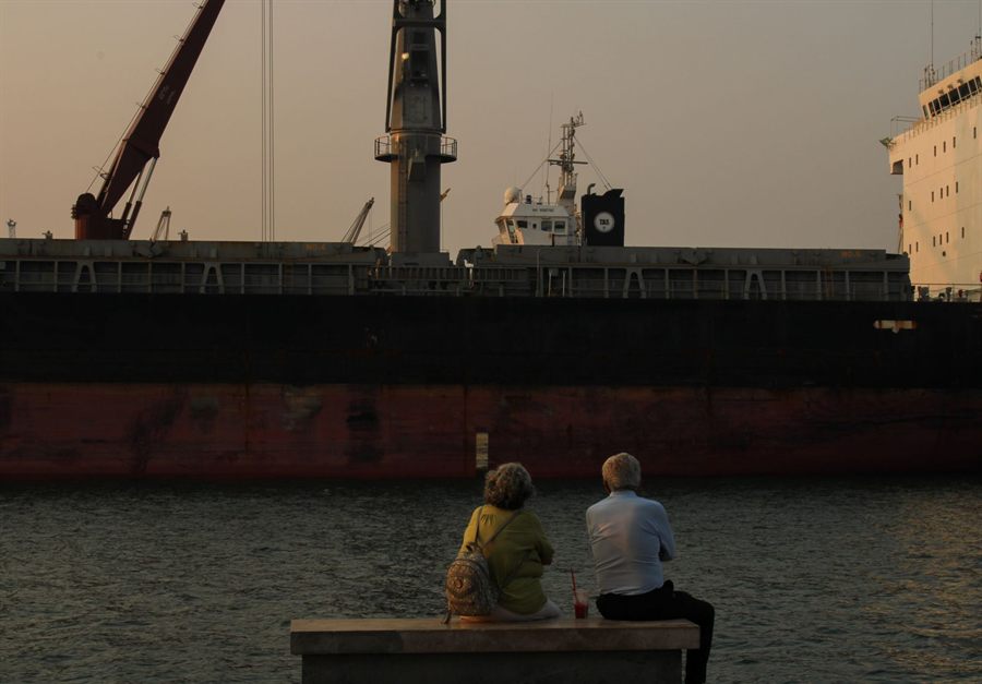 Older couple sitting by the water watching a ship at dusk