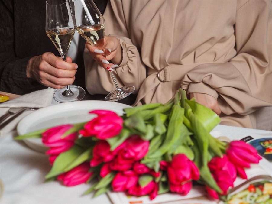 Couple toasting with champagne over a bouquet of pink tulips